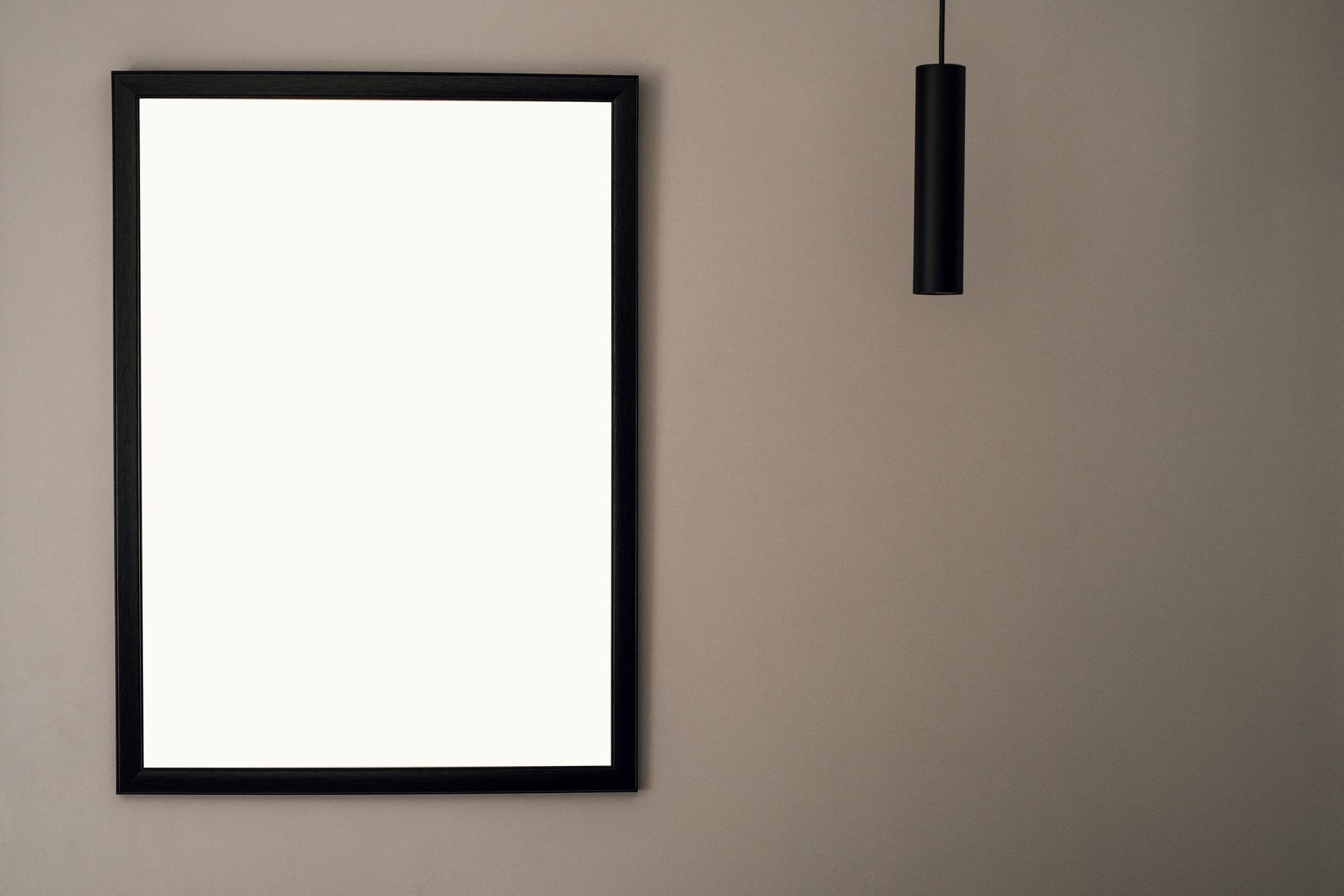 A minimalist picture frame on a neutral wall with hanging light and ample copy space.