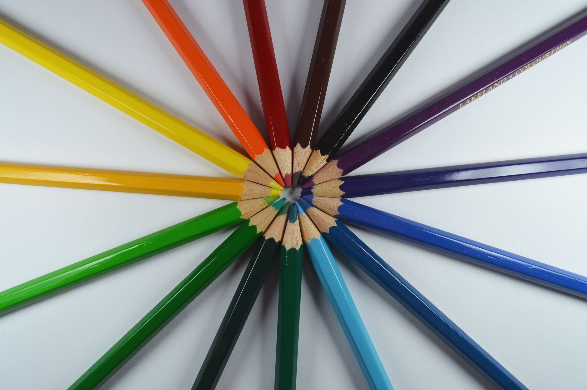 Circle of colorful pencils creatively displayed on a white background.