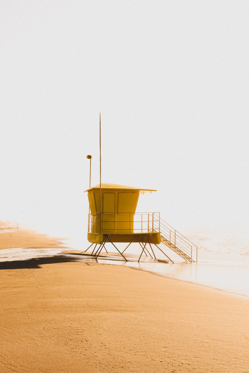 A lone yellow lifeguard tower on a deserted beach at sunset, creating a tranquil scene in Castelldefels.
