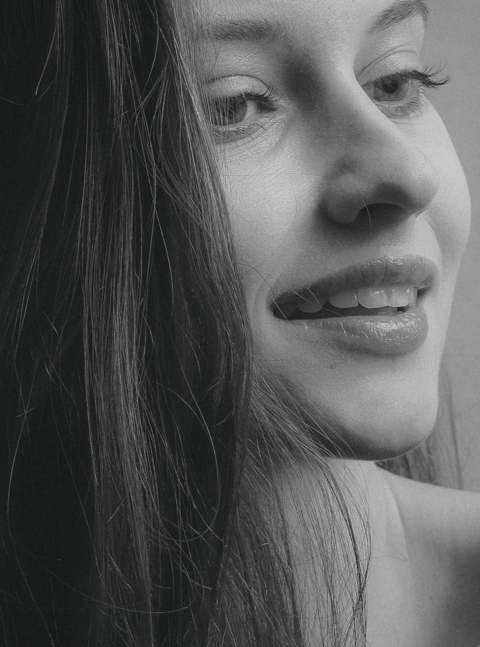 Monochrome close-up portrait of a smiling woman, with striking facial features.