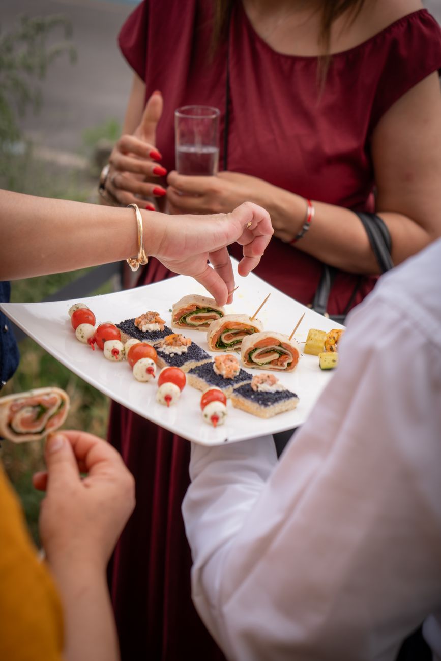 Gourmet appetizers served at an outdoor event with people enjoying the ambiance.
