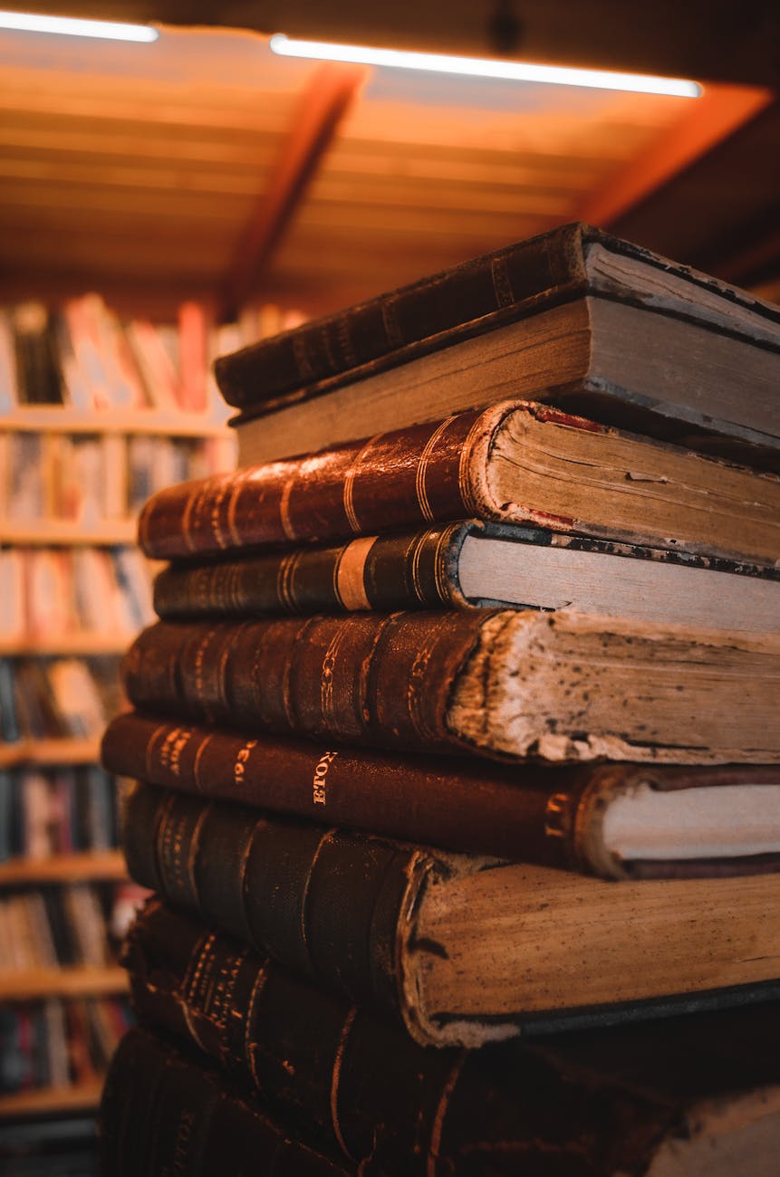 A close-up view of a stack of vintage books with a warm and nostalgic ambiance in a wooden library setting.
