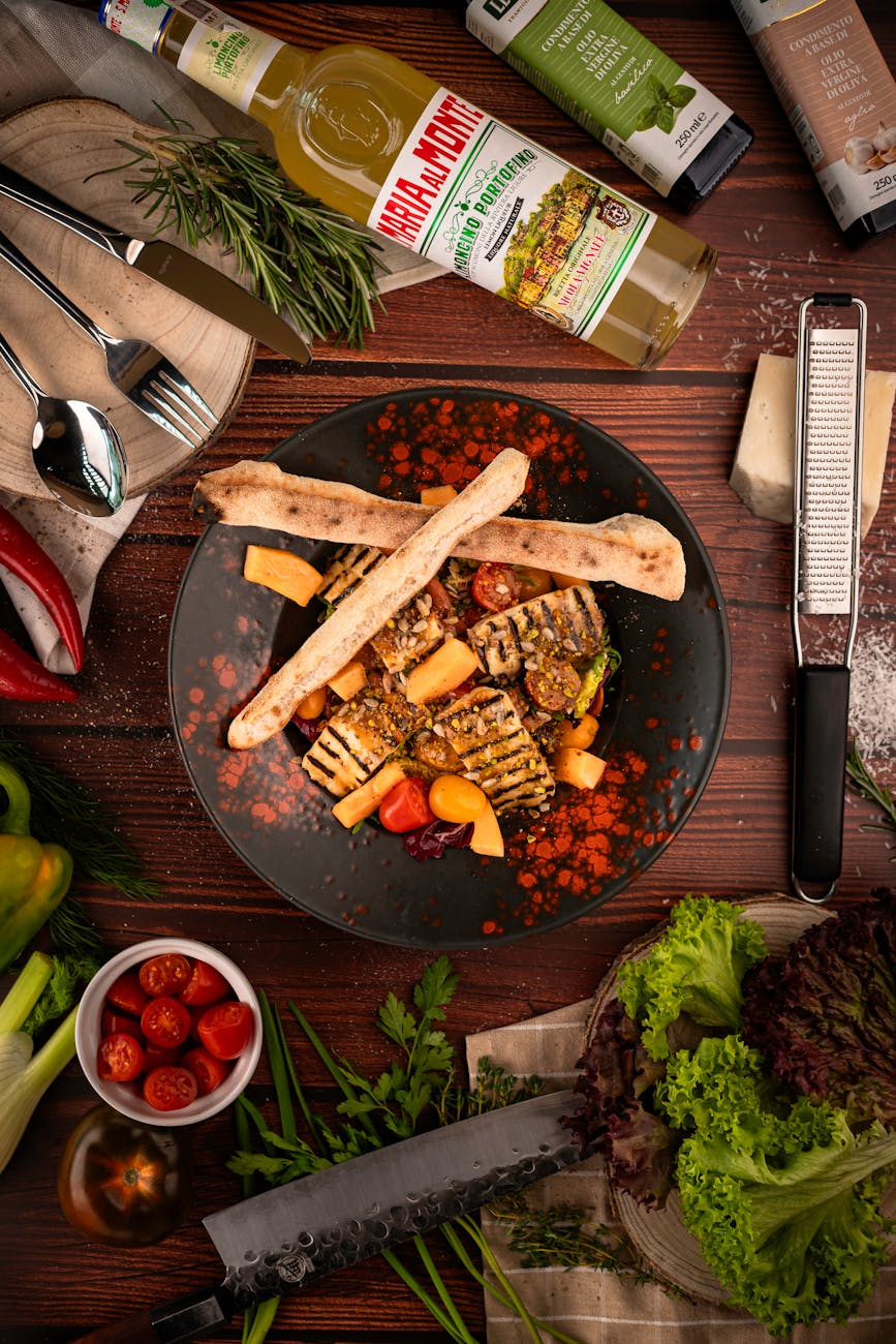 Artistic presentation of a gourmet salad with grilled vegetables, flatbread, and fresh herbs on a wooden table.