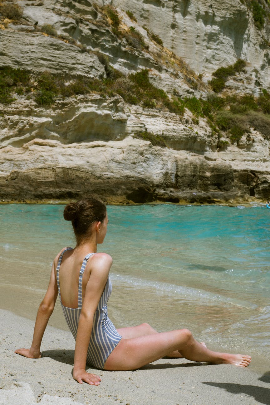 Woman relaxing on a serene beach in Tropea, Italy, with turquoise waters and rocky cliffs.