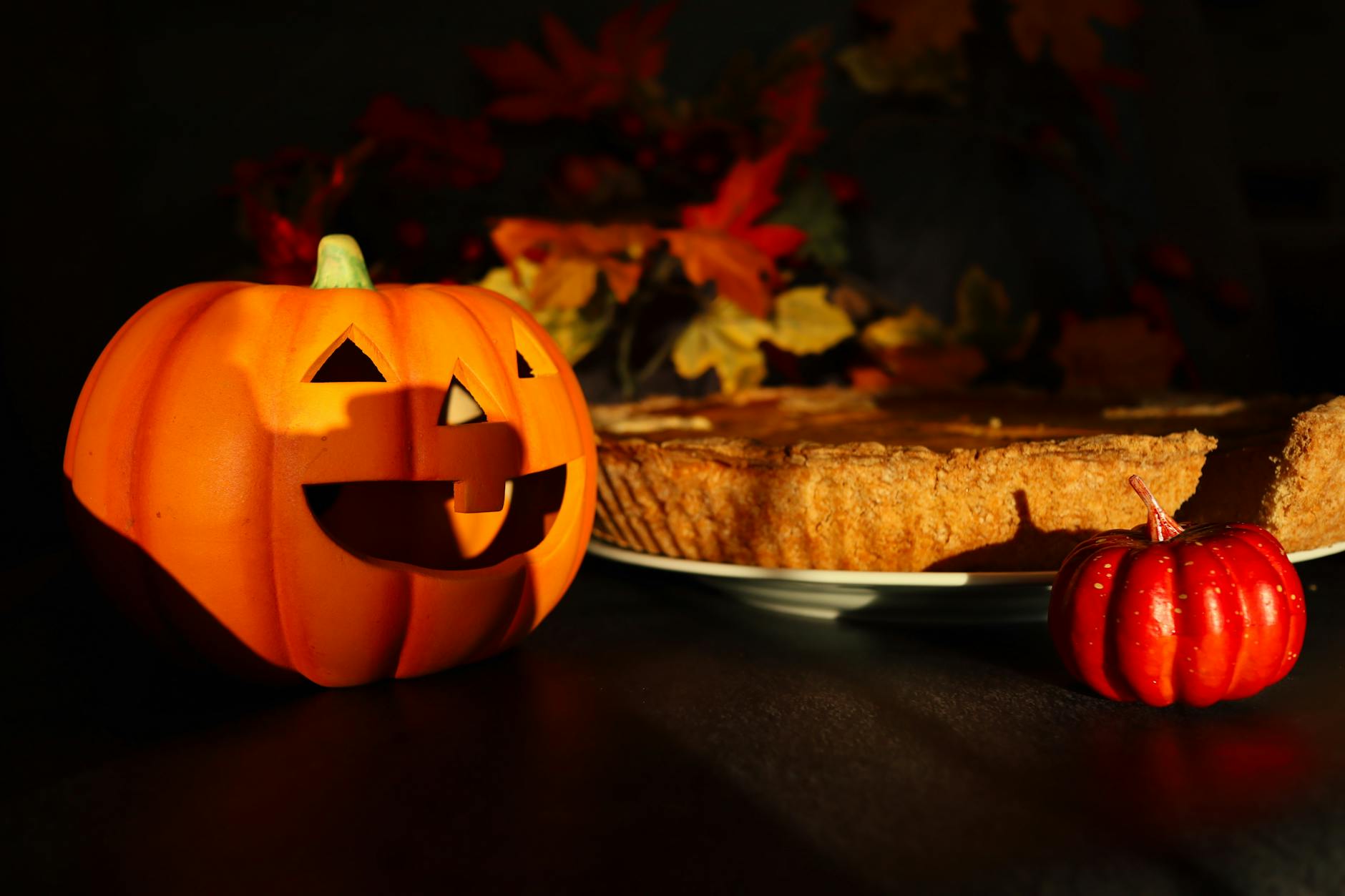 Warm autumn scene featuring a Jack-o'-lantern and pumpkin pie, perfect for Halloween home decor.