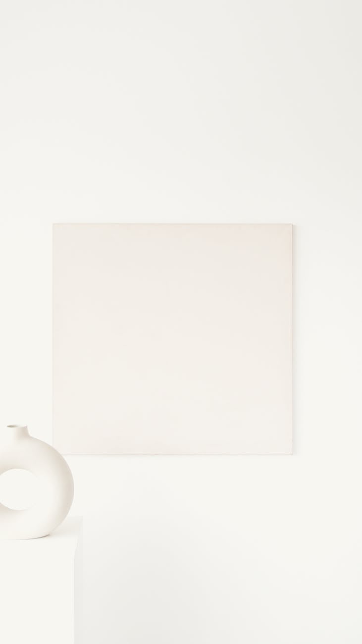 A minimalist interior featuring abstract art and a modern vase on a white surface.