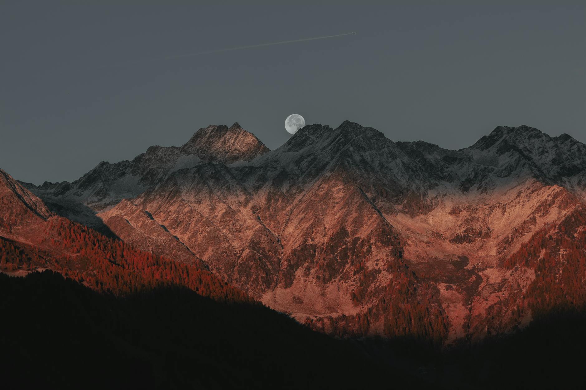 Stunning view of mountain peaks under moonlight with a twilight glow creating a dramatic landscape.