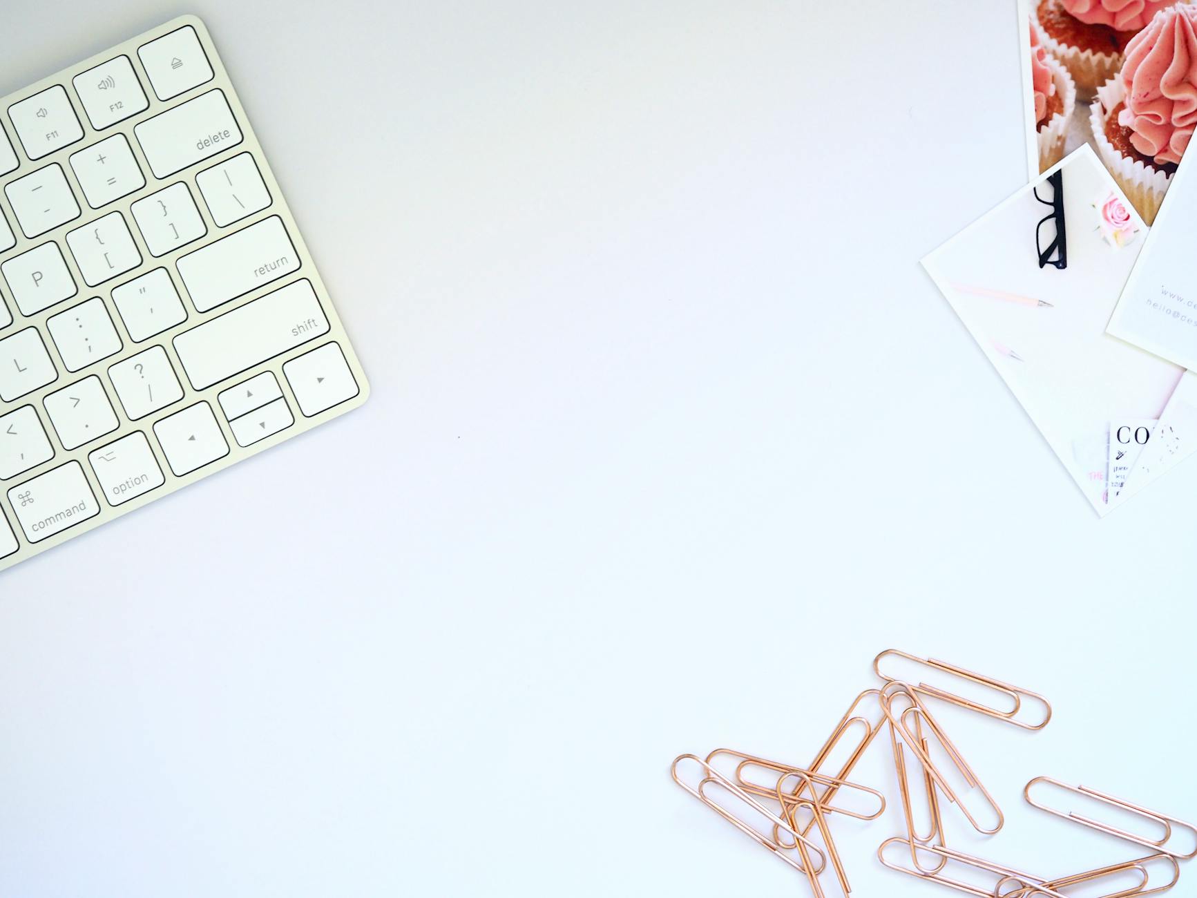 Clean and organized workspace featuring a keyboard and rose gold paper clips, perfect for design inspiration.