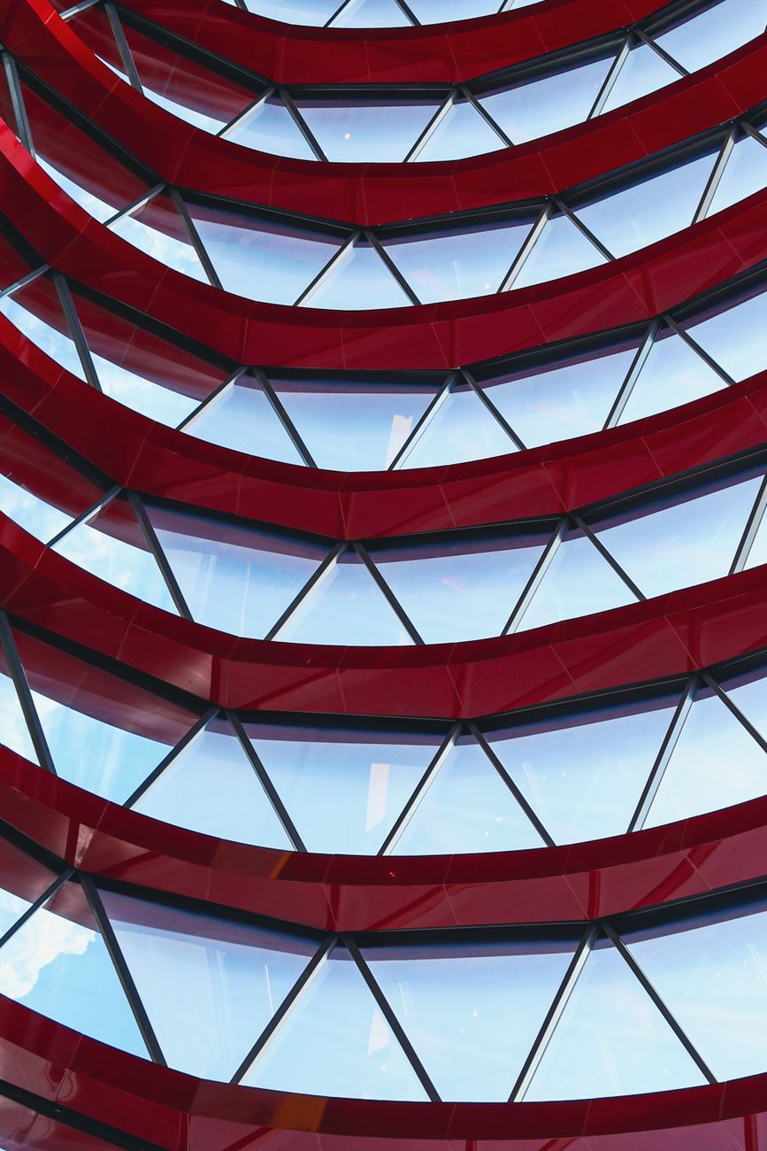 Dynamic red and glass architectural facade with geometric patterns in a modern style.