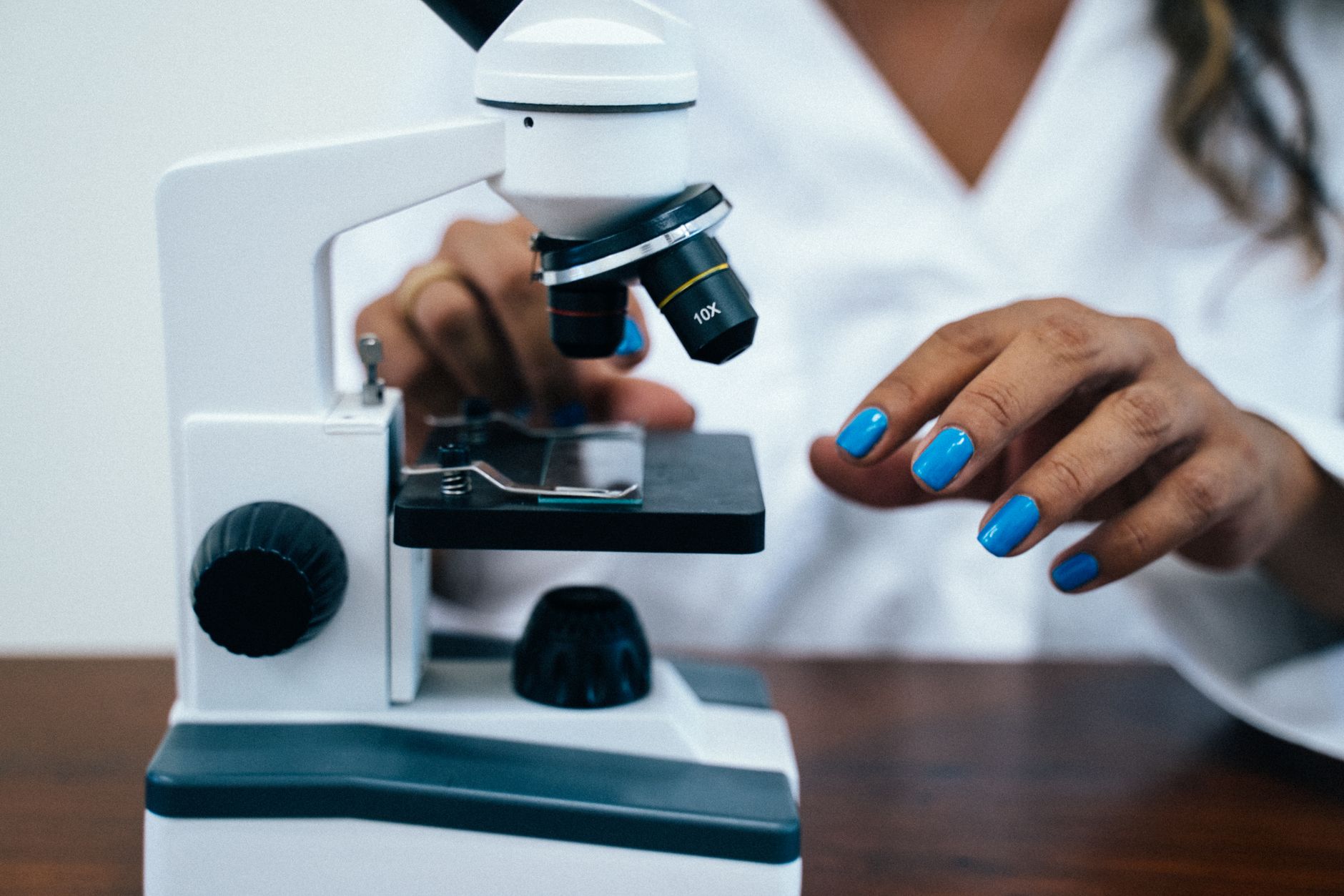 A woman uses a microscope in a lab setting, focusing on details and precision.