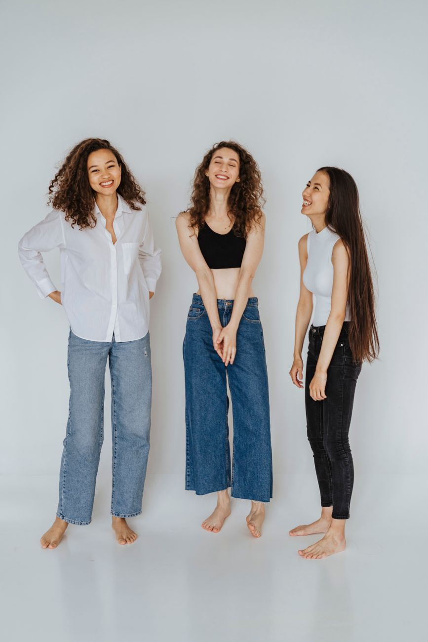 Group of young women posing joyfully in studio, showcasing fashion and diversity.