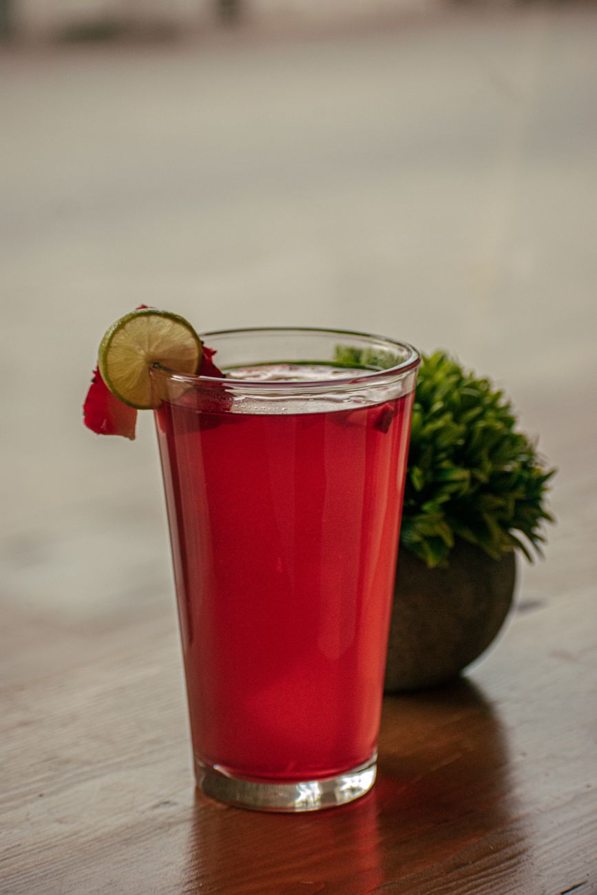 A vibrant red cocktail with lime on a wooden table, perfect for any occasion.