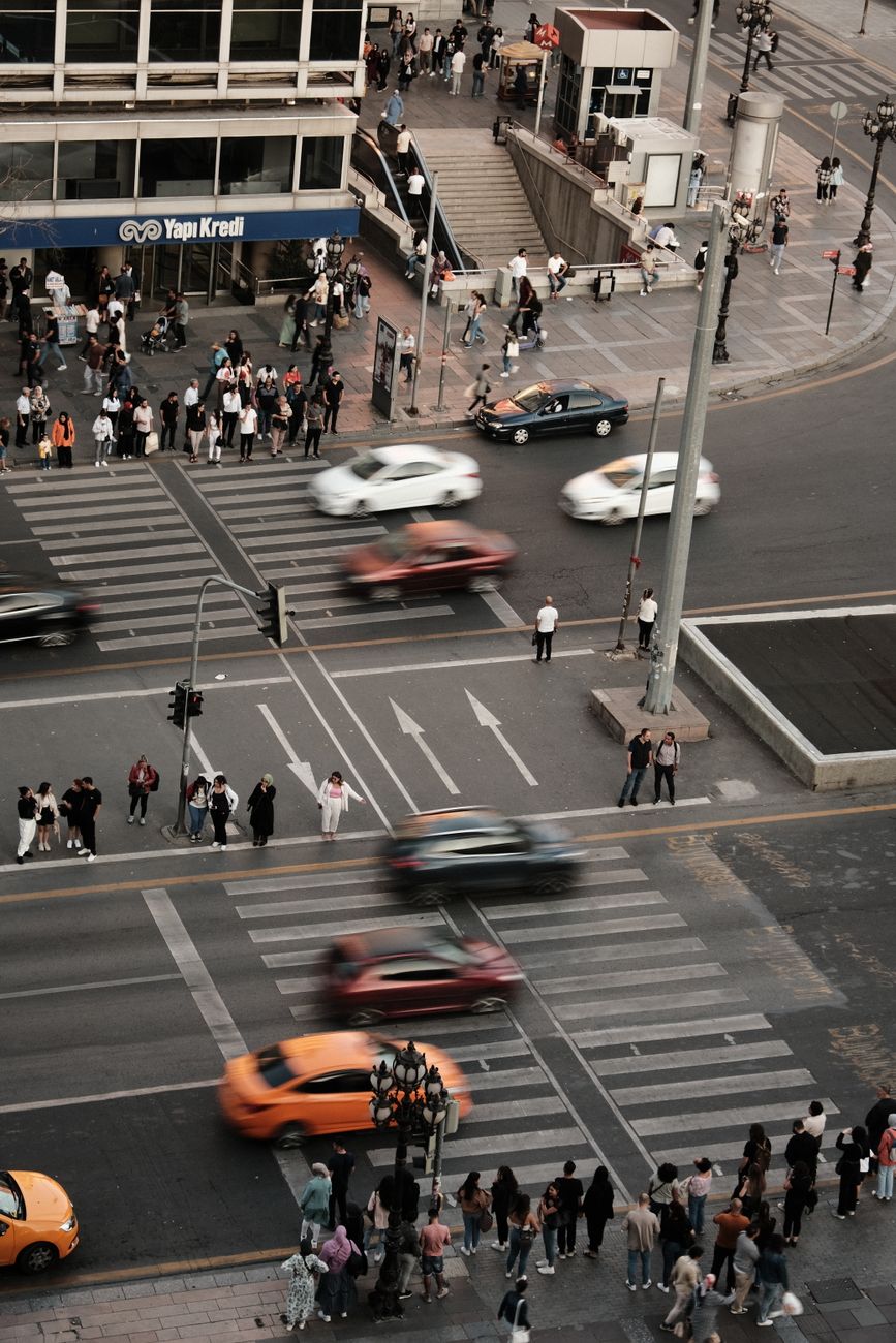 A bustling city intersection with blurred motion of cars and people waiting to cross.