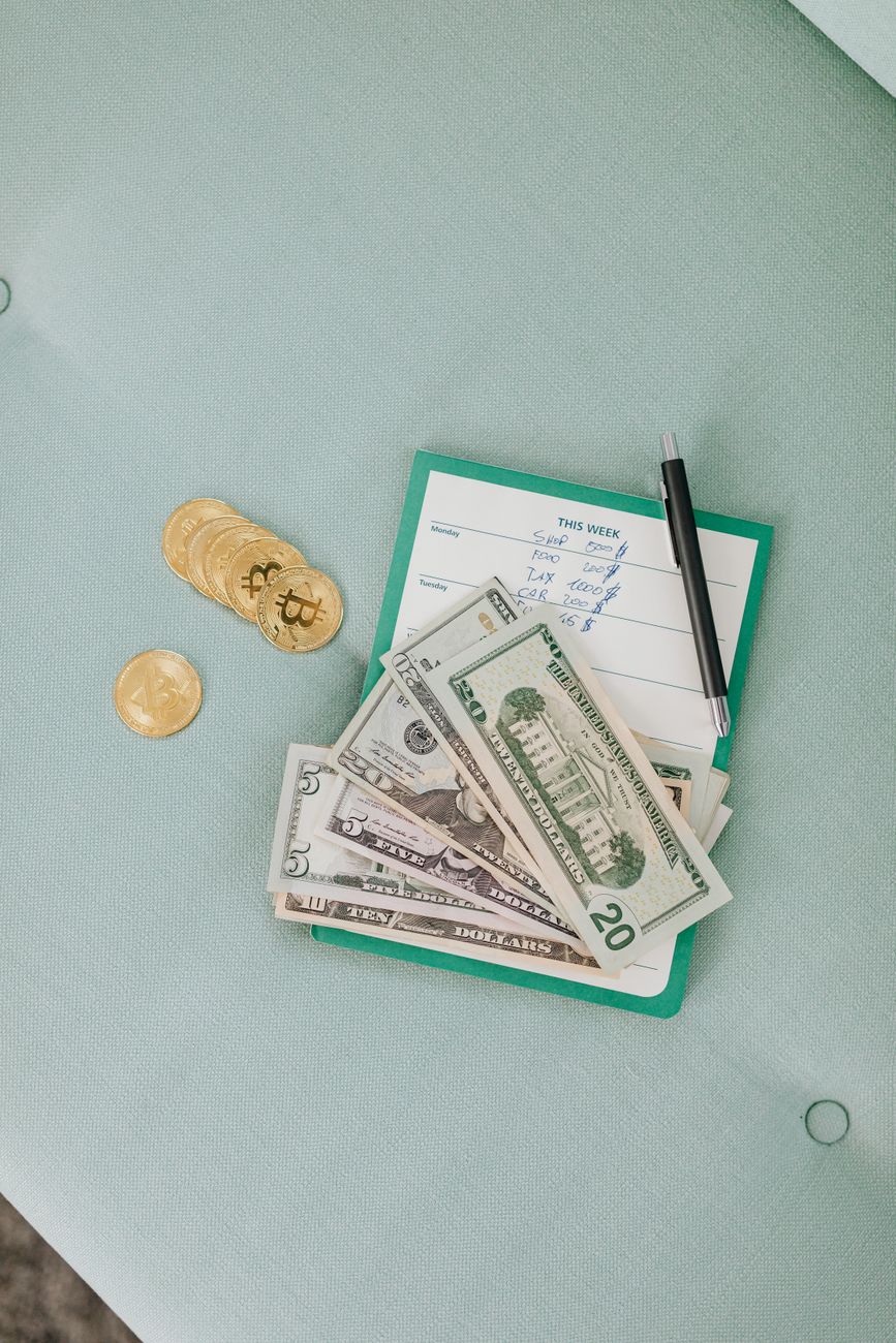 Close-up of US dollar bills, bitcoins, and a pen on calendar planner.