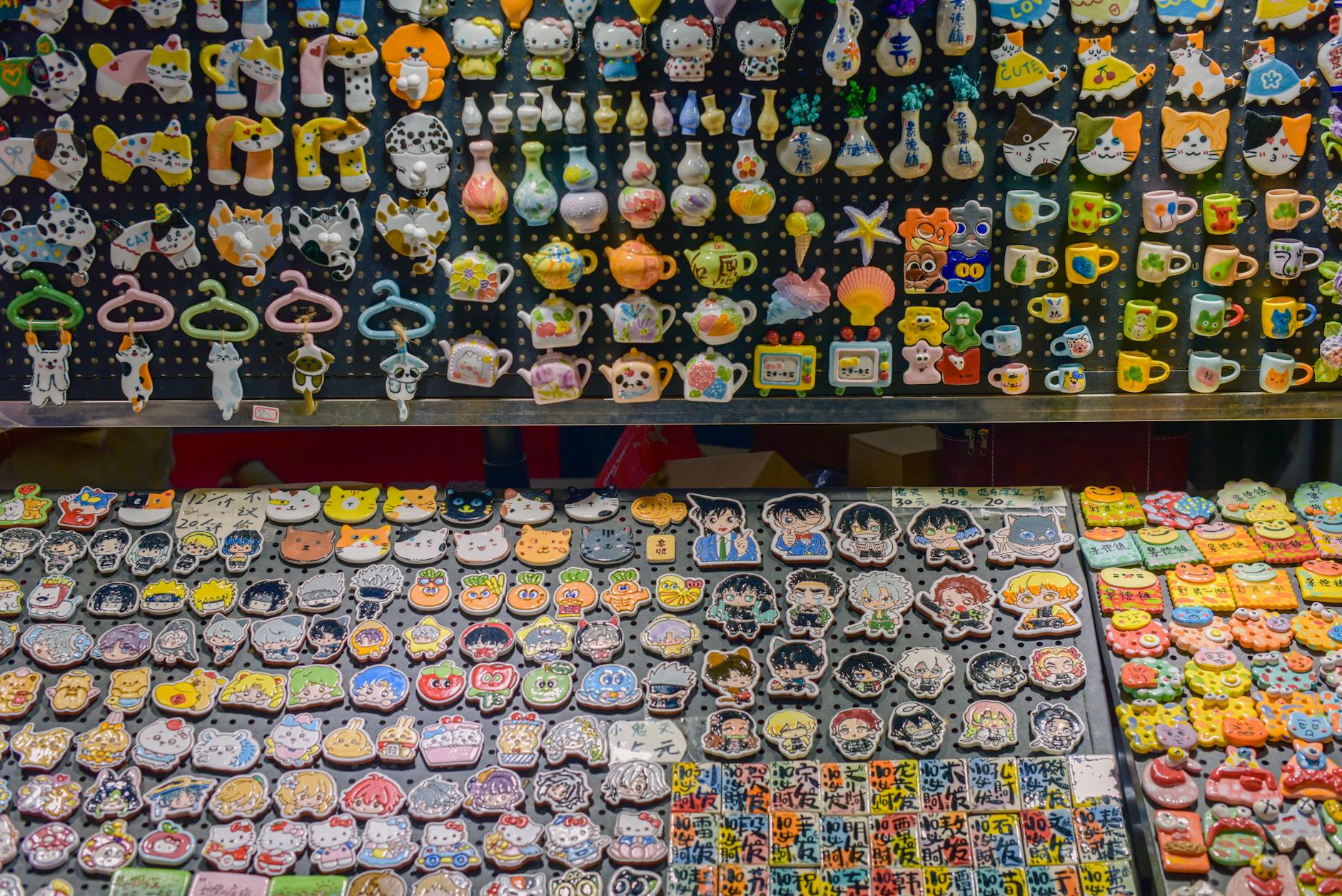 Vibrant handcrafted ceramic fridge magnets featuring animals, characters, and teapots on market display.
