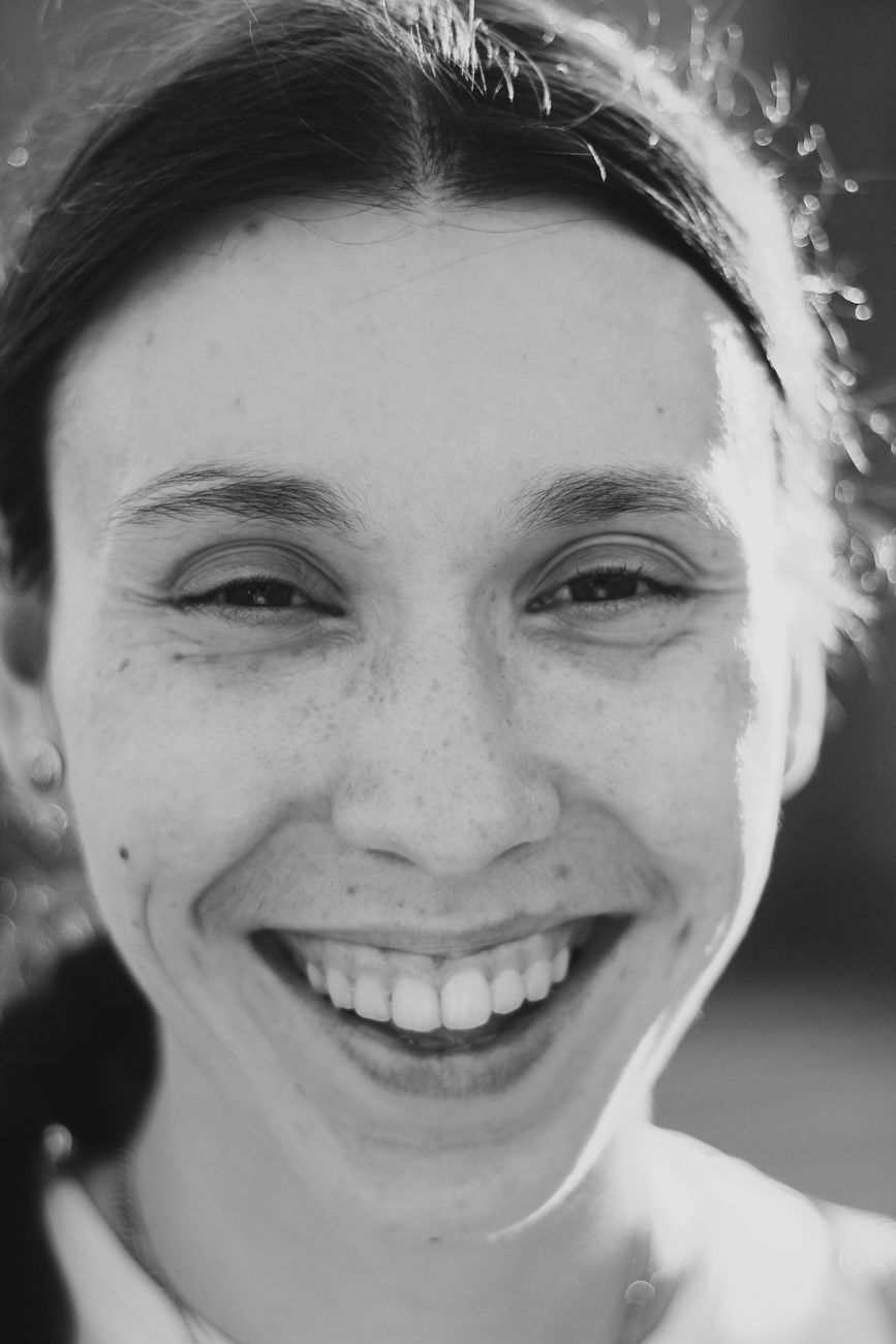Close-up black and white portrait featuring a smiling woman with joyful expression.